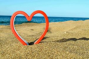 a heart shaped metal object on the beach photo