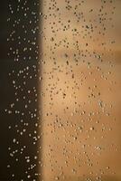 el fondo abstracto dejó caer el movimiento de parada de agua y goteó al suelo desde la ducha sobre un fondo marrón naranja borroso a la luz exterior. foto