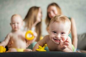 Two young mothers are playing with their happy kids in the room on the sofa. Happy baby laughs photo