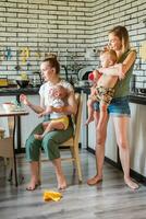 Two young mothers together feed their happy babies milk porridge in the kitchen photo