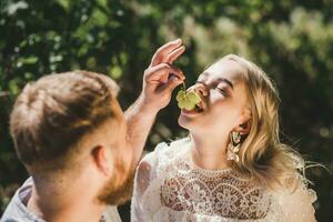 Happy couple spend time together and feed each other grapes in summer outdoors photo