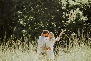 Happy and loving couple kissing and throwing hat up in summer photo