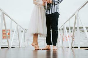 Feet of the newlyweds on the pier. Legs of the bride and groom barefoot on the wharf. photo