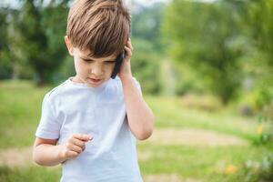 the child speaks on the phone in nature photo
