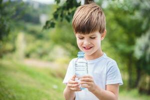 cool baby drinks clean water from a bottle on a sunny day in nature photo