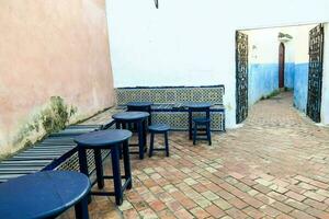 a blue and white tiled alleyway with blue chairs photo