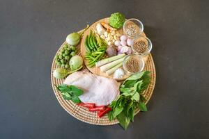 Flatlay top table of Performing ingredient, seasoning of Chicken Green Curry and Ingredient, garlic, shallot, galangal, lemon grass, basil, bergamot, Thai eggplant. photo