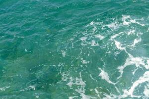 the ocean is blue and green with white waves photo