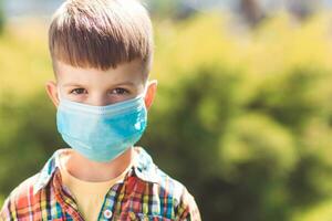 Portrait of a little boy in a protective mask on the street during the coronavirus and Covid pandemic - 19 photo