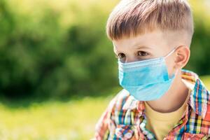 Portrait of a young child in a medical mask on the street during the coronavirus and Covid pandemic - 19 photo