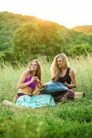 Young girls play and sing on the musical instrument Handpan. Practice meditation at sunset photo