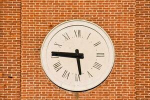 a large clock on a brick wall with roman numerals photo