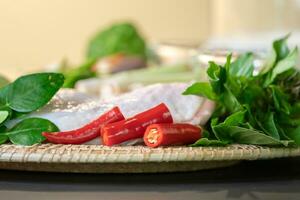 Focusing on finger chillies are placed between basils and green herbs. And having other food ingredients behind them. photo