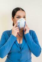 Beautiful girl puts on a medical mask on her face in a photo studio Protection against coronavirus and Covid-19