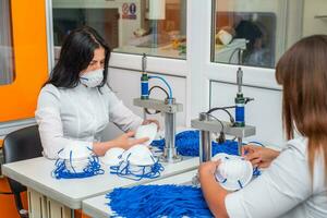 mujer trabajo a un máquina para el fabricar de médico mascaras con nanofibras y soldar bucles a ellos con ultrasonido. coronovirus y covid-19 prevención foto