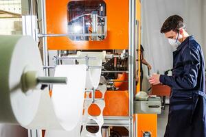 A worker stands at the machine in a factory for the manufacture of medical masks with nanofiber. Coronovirus and Covid-19 Protection photo