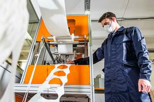 A worker stands at the machine in a factory for the manufacture of medical masks with nanofiber. Coronovirus and Covid-19 Protection photo