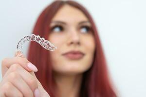 A woman with a beautiful smile holds aligners in her hand photo