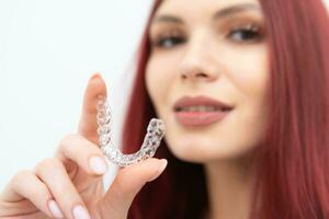 A girl with a beautiful smile holds aligners in her hand photo