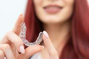 A girl with a beautiful smile holds aligners in her hand photo
