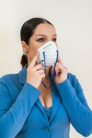 Beautiful girl puts on a medical mask on her face in a photo studio Protection against coronavirus and Covid-19