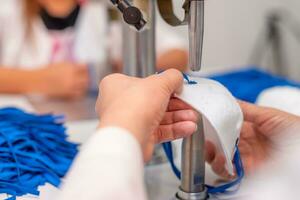 mujer trabajo a un máquina para el fabricar de médico mascaras con nanofibras y soldar bucles a ellos con ultrasonido. coronovirus y covid-19 prevención foto