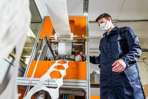 A man works at a machine for the manufacture of medical masks with nanofiber. Coronovirus and Covid-19 Prevention photo