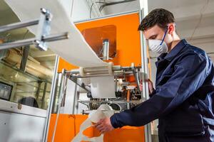 A man works at a machine for the manufacture of medical masks with nanofiber. Coronovirus and Covid-19 Prevention photo