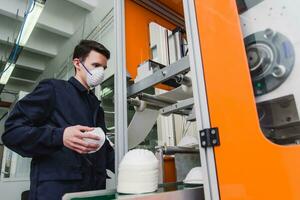 un trabajador soportes a el máquina en un fábrica para el fabricar de médico mascaras con nanofibra. coronovirus y covid-19 proteccion foto
