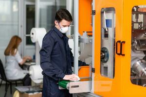 A man works at a machine for the manufacture of medical masks with nanofiber. Coronovirus and Covid-19 Prevention photo