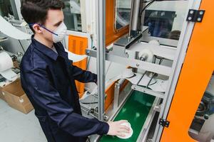 un trabajador soportes a el máquina en un fábrica para el fabricar de médico mascaras con nanofibra. coronovirus y covid-19 proteccion foto
