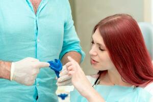 Doctor orthodontist shows the patient the result of the casts of her teeth photo