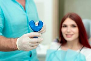 Doctor orthodontist shows the patient the result of the casts of her teeth photo