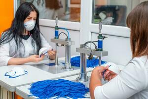 un mujer trabajos a un máquina para el fabricar de médico mascaras con nanofibra y soldar bucles a ellos con ultrasonido. coronovirus y covid-19 prevención foto