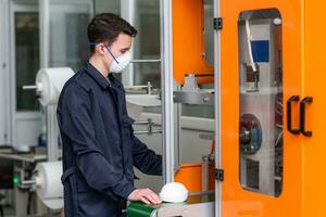 A man works at a machine for the manufacture of medical masks with nanofiber. Coronovirus and Covid-19 Prevention photo