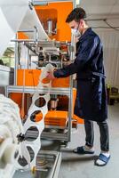 A man works at a machine for the manufacture of medical masks with nanofiber. Coronovirus and Covid-19 Prevention photo