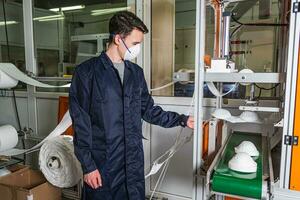A man works at a machine for the manufacture of medical masks with nanofiber. Coronovirus and Covid-19 Prevention photo
