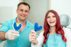 contento médico dentista con su paciente espectáculo el resultado de impresiones de su dientes en un cuchara con silicona material foto