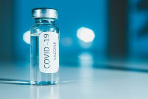 Vaccination against coronavirus COVID - 19. Vial on a blue background close-up. Concept. photo
