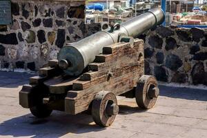 an old cannon on a wooden cart in front of a stone wall photo