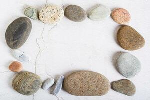 Template frame made of smooth sea stones on a light background top view photo