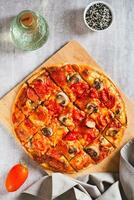American St. Louis Style pizza with bacon, mushrooms and tomatoes on a board top and vertical view photo