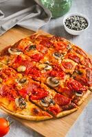 American St. Louis Style pizza with bacon, mushrooms and tomatoes on a board vertical view photo