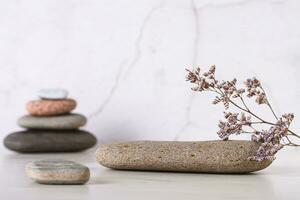 Pedestal pattern of smooth flat sea stone and dried flowers on table photo