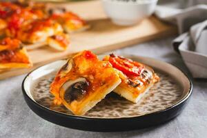 Pieces of St. Louis Style pizza with bacon, mushrooms, tomatoes and peppers on a plate photo