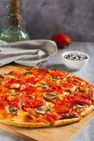 S t. Luis estilo Pizza con tocino, hongos, Tomates y pimientos en un tablero vertical ver foto