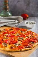 St. Louis Style pizza with bacon, mushrooms, tomatoes and peppers on a board vertical view photo