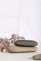 Pattern of smooth flat sea stones and dried flowers on the table vertical view photo
