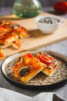 Pieces of St. Louis Style pizza with bacon, mushrooms, tomatoes and peppers on a plate vertical view photo