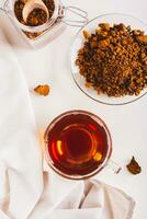 Healing tea from wild birch chaga mushroom in a cup on the table top and vertical view photo